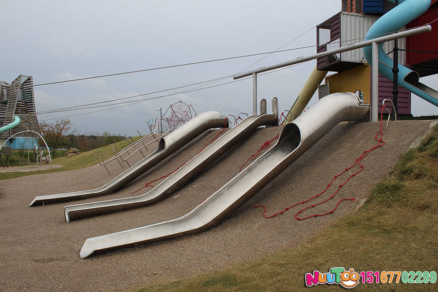 Niños en verano para jugar a toboganes de acero inoxidable al aire libre